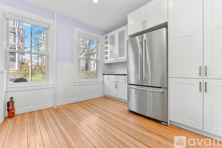 A kitchen with white cabinets and a stainless steel refrigerator.