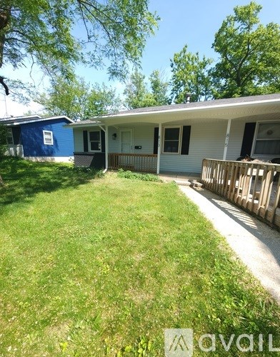 A blue house with a white porch and a green lawn.