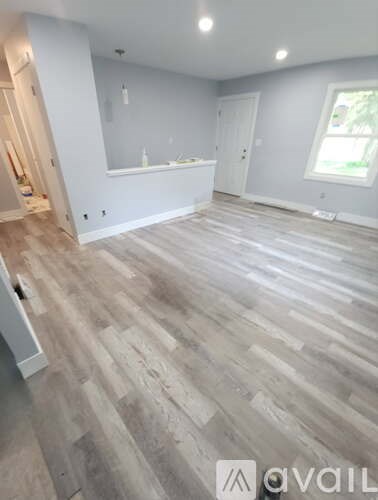 A room with wooden flooring and white walls.