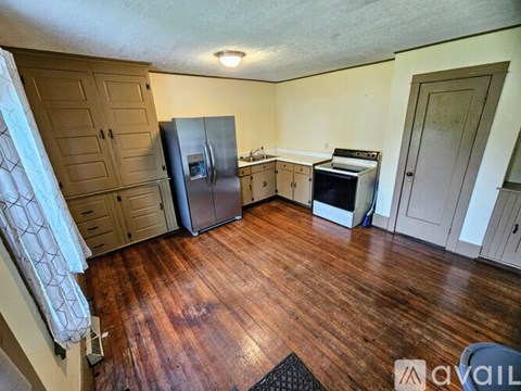 A kitchen with wooden floors and a refrigerator.