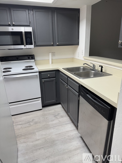 A kitchen with a white stove top oven and a white dishwasher.