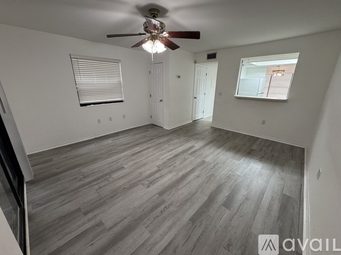 A room with a ceiling fan and wooden flooring.