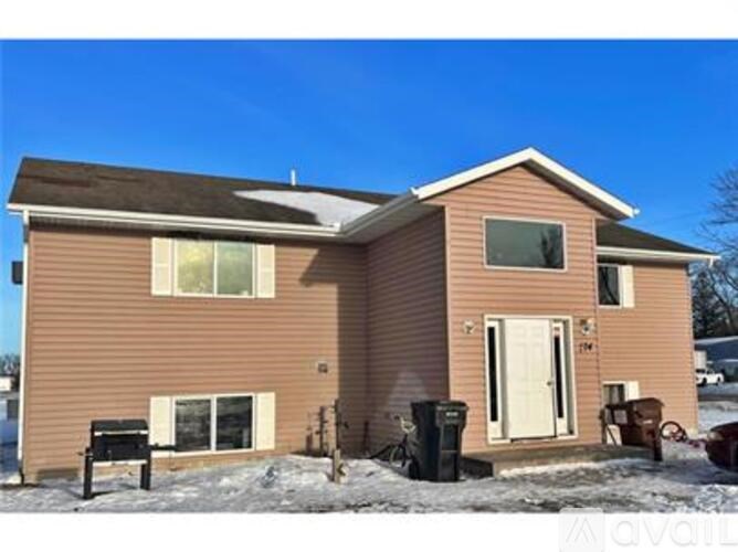 A house with a brown siding and a white door is surrounded by snow.