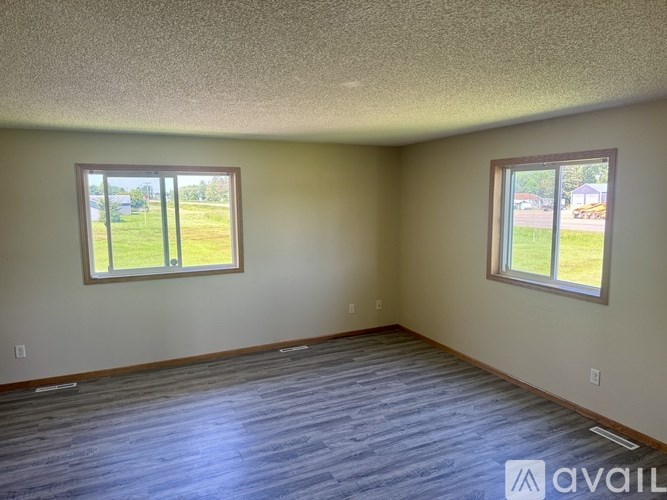 A room with two windows and a wooden floor.