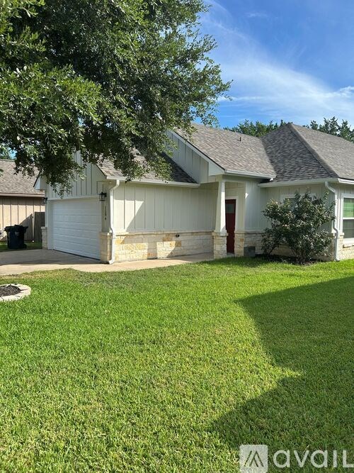A house with a white garage door and a tree in front.