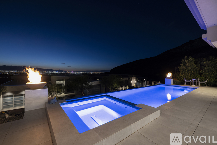 A swimming pool lit up at night with a mountain in the background.