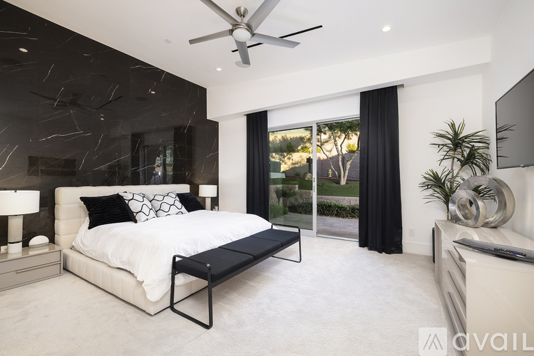 A modern bedroom with a large bed and a ceiling fan.
