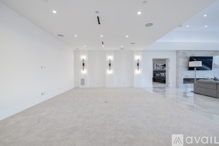 A spacious living room with a grey carpet and white walls.