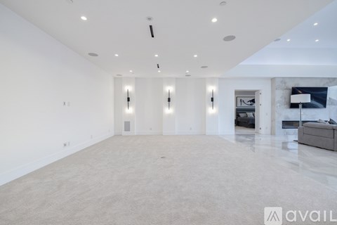 A spacious living room with a grey carpet and white walls.