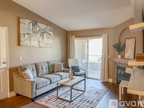 A living room with a grey couch and a painting on the wall.