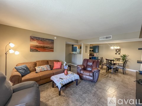 A living room with a brown couch, a red chair, and a painting on the wall.