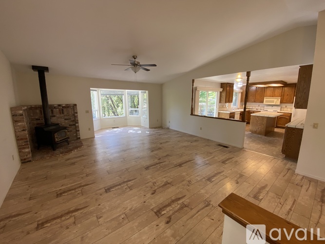 A spacious living room with wood flooring and a fireplace.