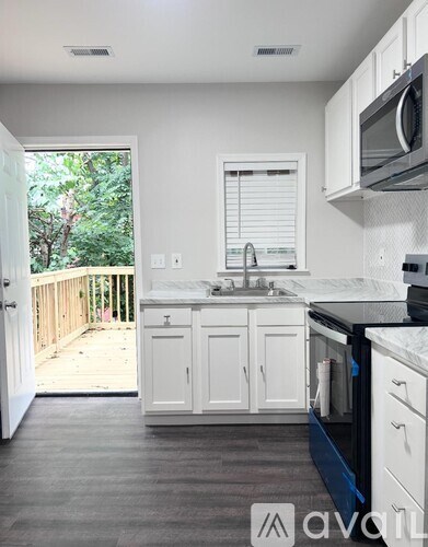 A kitchen with white cabinets and a black countertop.