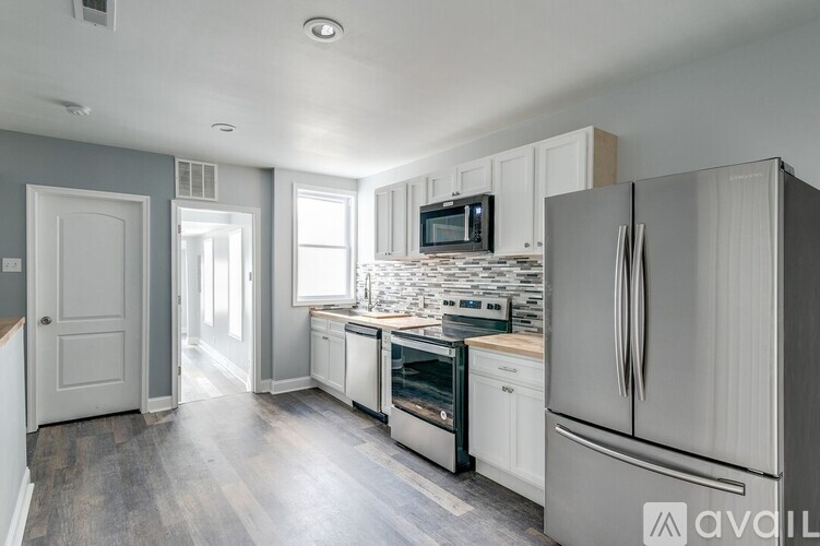 A kitchen with white appliances and a grey wall.