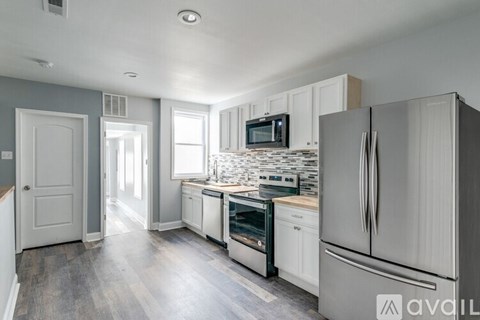 A kitchen with white appliances and a grey wall.