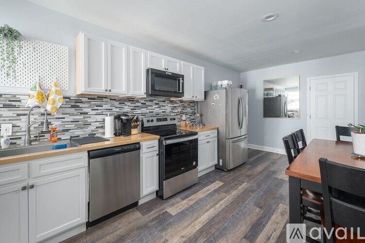 A kitchen with a stone backsplash and stainless steel appliances.