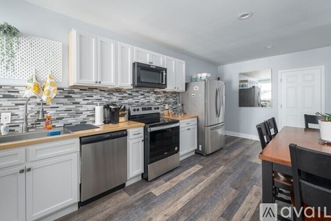 A kitchen with a stone backsplash and stainless steel appliances.