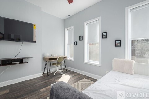 A bedroom with a bed, desk, chair, and a window.