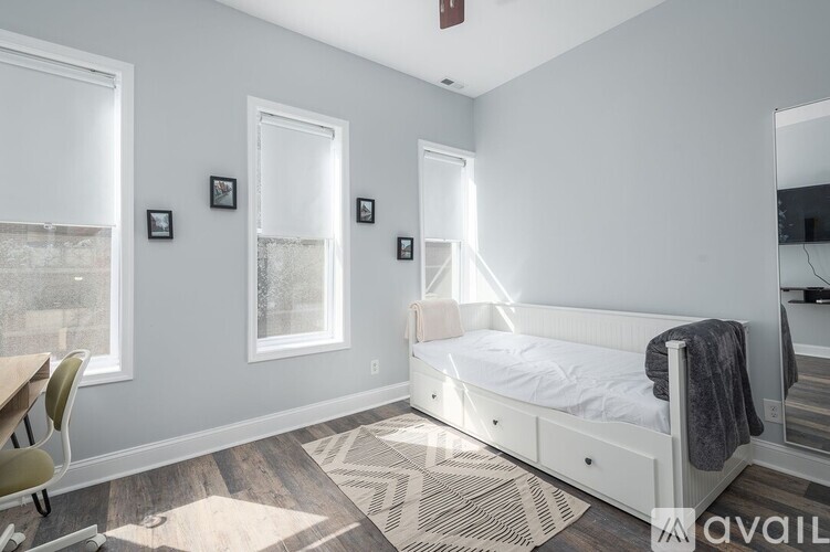 A bedroom with a bed, chair, and pictures on the wall.