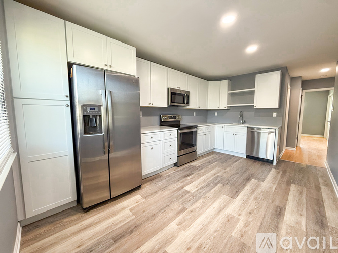 A kitchen with white cabinets and a wooden floor.