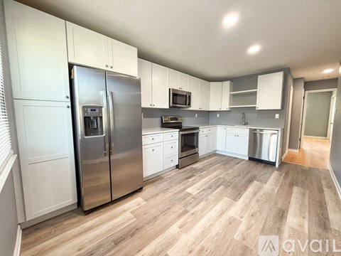 A kitchen with white cabinets and a wooden floor.