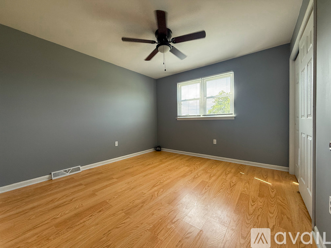 A room with a ceiling fan and wooden flooring.