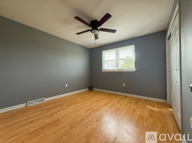 A room with a ceiling fan and wooden flooring.