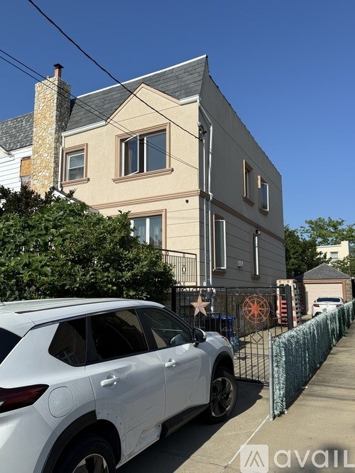 A white car is parked in front of a two-story house.