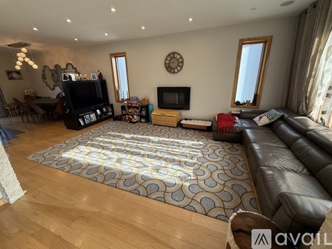 A living room with a leather couch and a patterned rug.