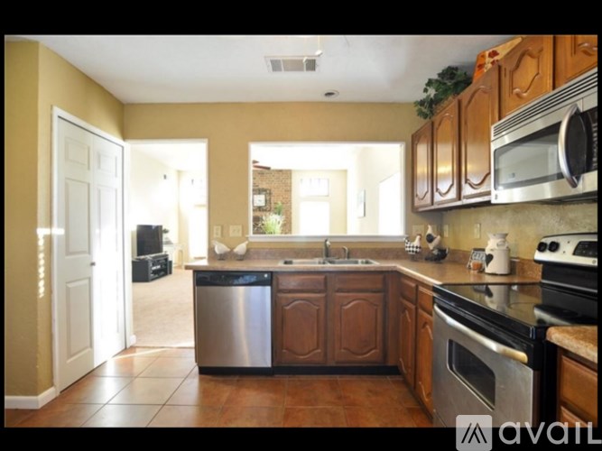 A kitchen with wooden cabinets and a stainless steel trash can.