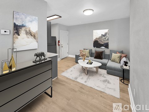 A modern living room with a grey couch, a coffee table, and a painting on the wall.