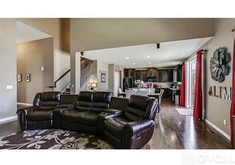 A living room with a black leather sofa and a rug.