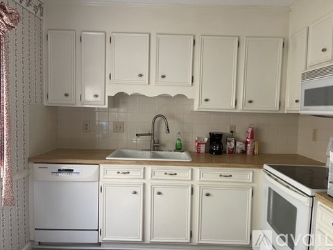 A kitchen with white cabinets and appliances.