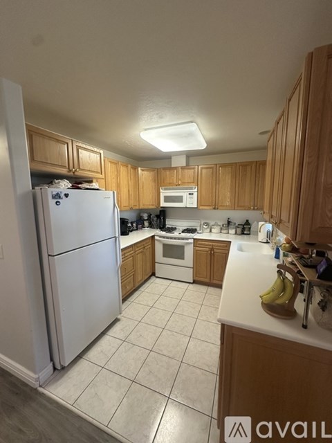 A kitchen with a white refrigerator and wooden cabinets.