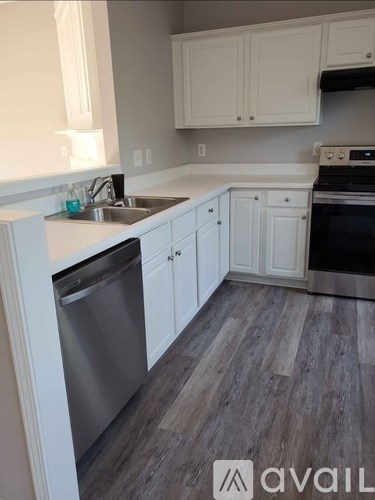 A kitchen with white cabinets and a wooden floor.