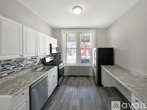 A kitchen with white cabinets and a marble countertop.