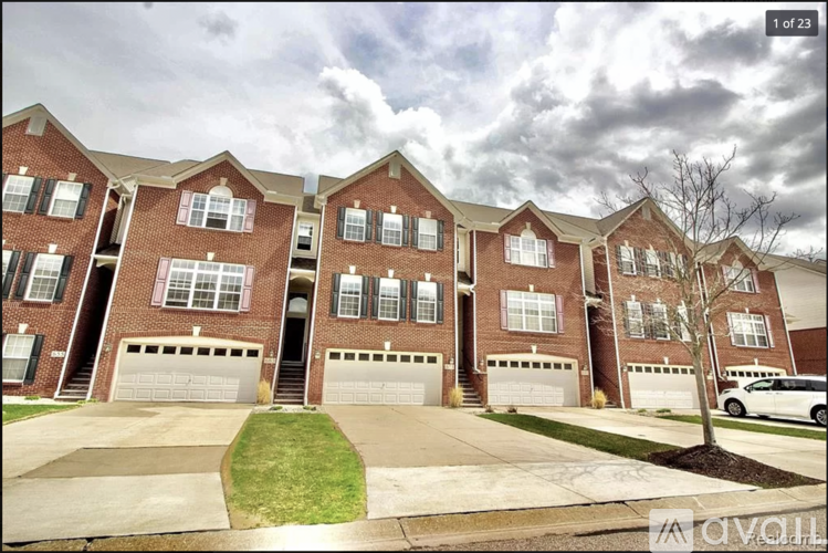 A large brick apartment building with multiple garages and a tree in front.