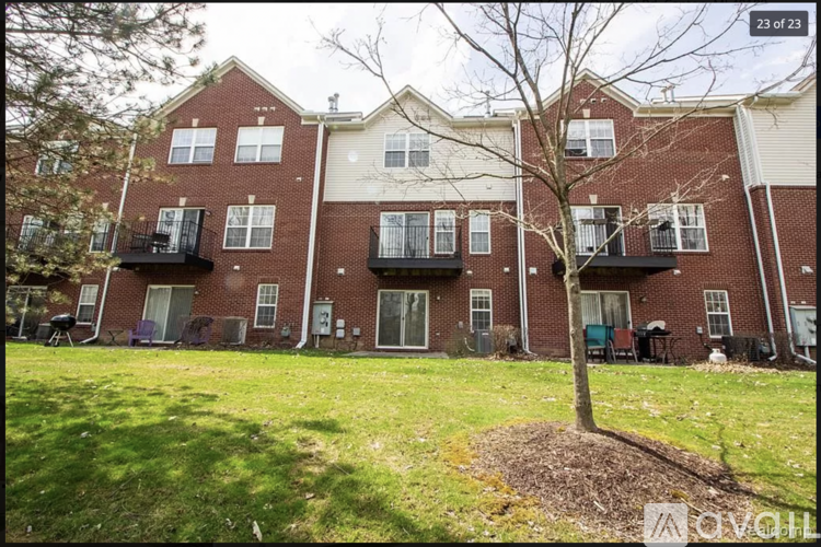 A tree in a mulched area in front of a brick building with balconies.