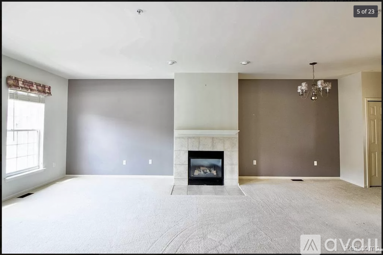 A spacious living room with a fireplace and a chandelier.