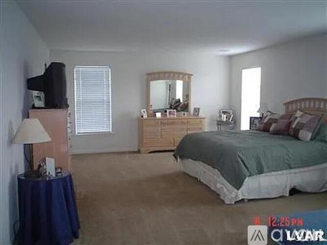 A bedroom with a bed, dresser, and mirror.