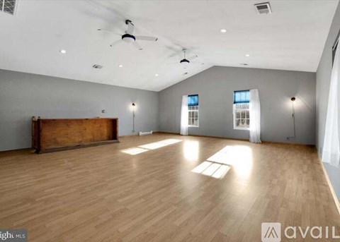 A spacious room with wooden flooring and a large window.