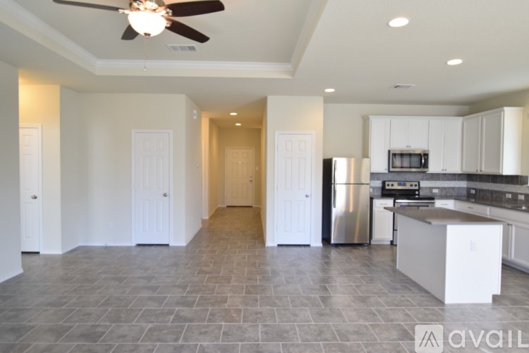 A spacious kitchen and living room with a fan on the ceiling.