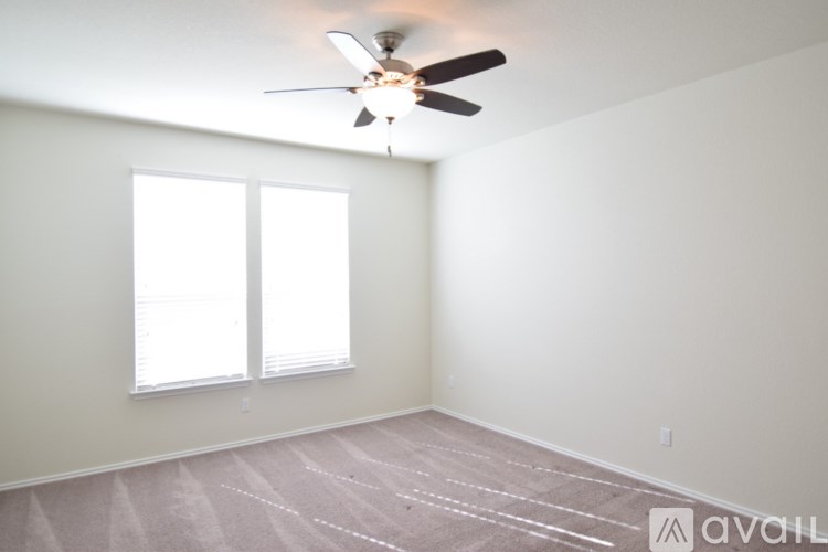 A room with a ceiling fan and two windows.