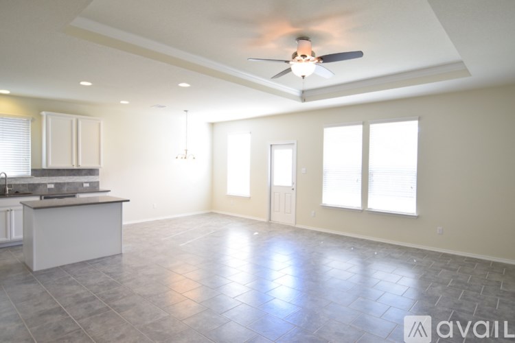 A spacious room with a kitchen area and a ceiling fan.