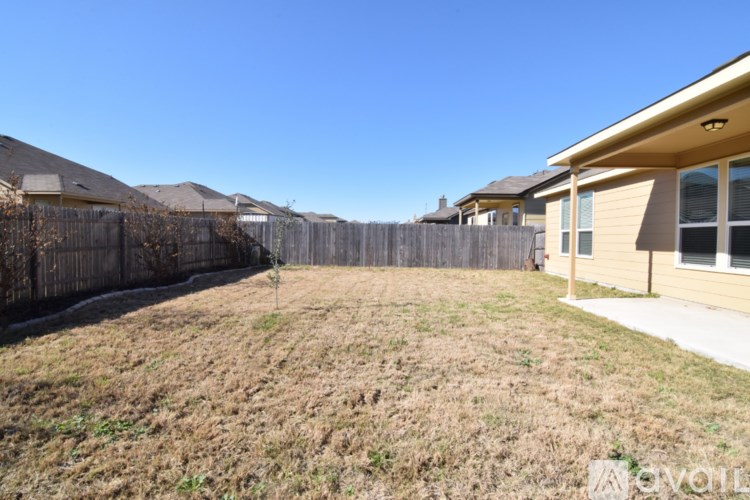 A backyard with a fence and a house in the background.