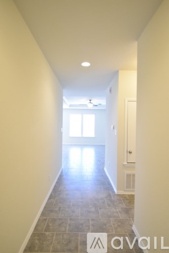 A long hallway with tiled floors and white walls.