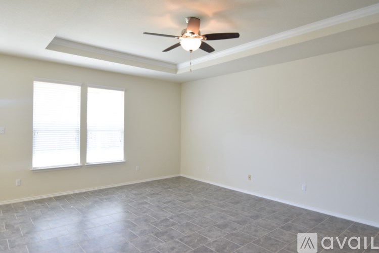 A spacious room with a ceiling fan and tiled flooring.