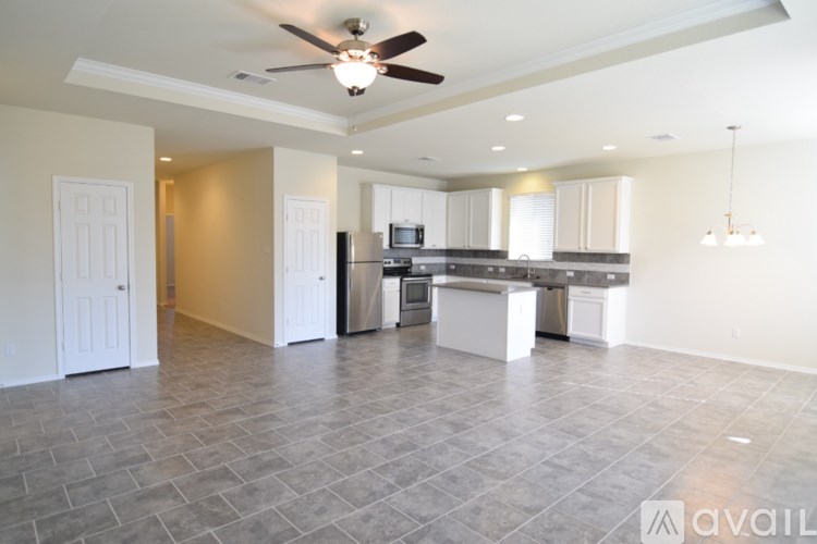 A spacious kitchen and living room with a ceiling fan and tiled flooring.