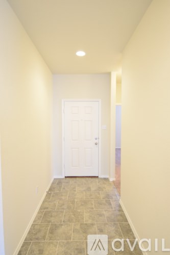 A hallway with a white door and tiled floor.
