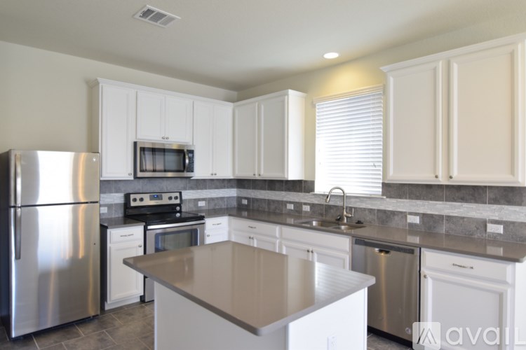 A kitchen with white cabinets and a stainless steel refrigerator.